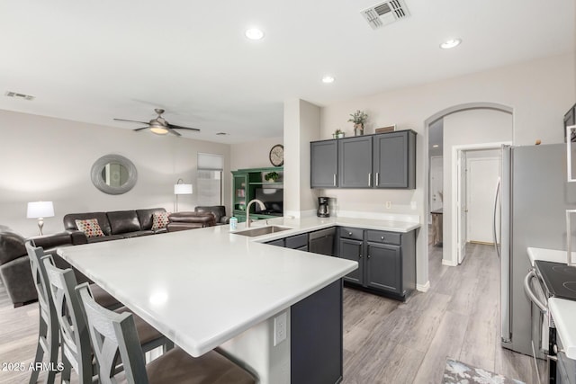 kitchen featuring sink, gray cabinets, a breakfast bar, appliances with stainless steel finishes, and light hardwood / wood-style floors