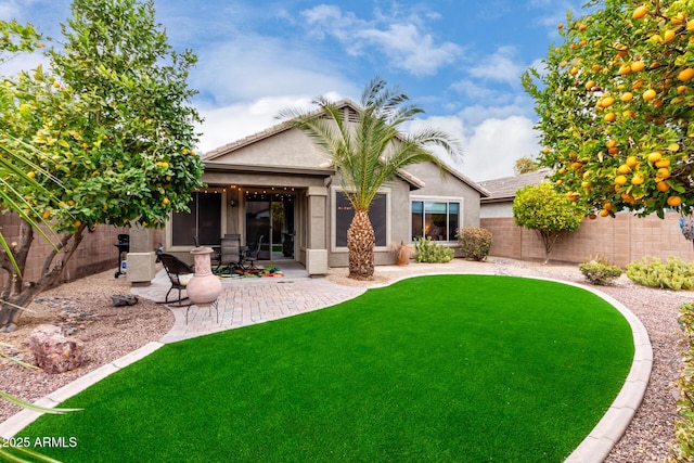 rear view of property featuring a lawn and a patio area