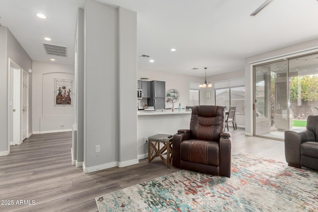 living room with wood-type flooring, sink, and an inviting chandelier