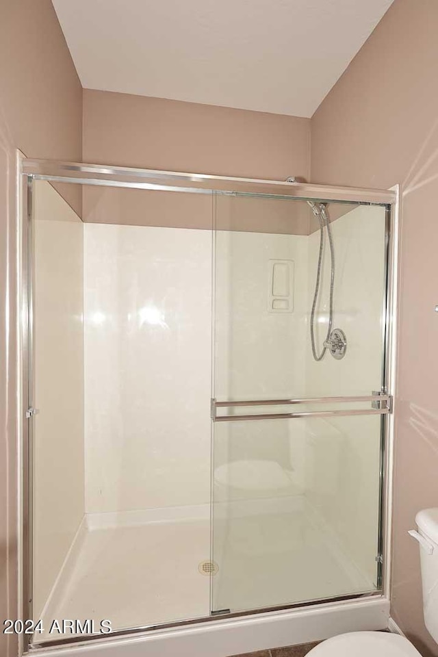 bathroom featuring a shower with shower door and toilet