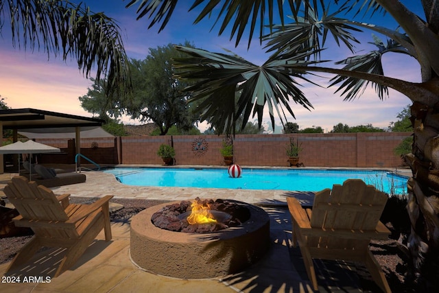 pool at dusk featuring a fire pit and a patio area