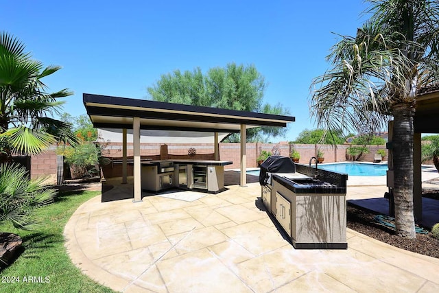 view of patio featuring a fenced in pool, area for grilling, and an outdoor bar