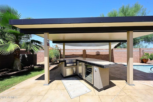 view of patio / terrace featuring a gazebo, a fenced in pool, and exterior kitchen