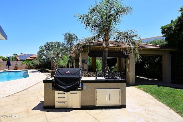 view of patio / terrace featuring an outdoor kitchen, a grill, a fenced in pool, and sink