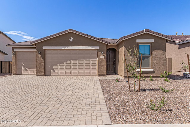 view of front facade featuring a tiled roof, decorative driveway, an attached garage, and stucco siding