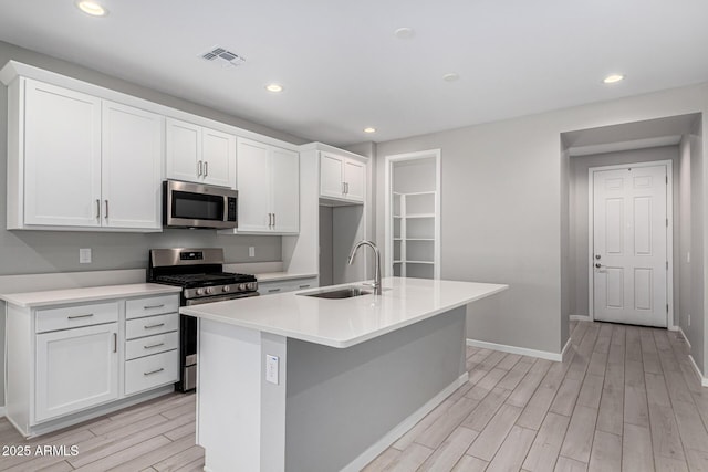 kitchen featuring visible vents, stainless steel appliances, wood finish floors, and a sink