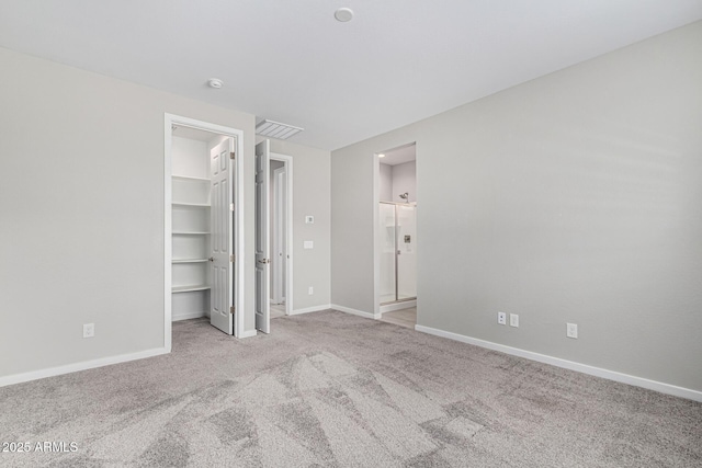 unfurnished bedroom with a spacious closet, visible vents, baseboards, carpet, and a closet