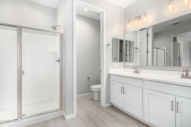 full bathroom featuring double vanity, a stall shower, toilet, and a sink