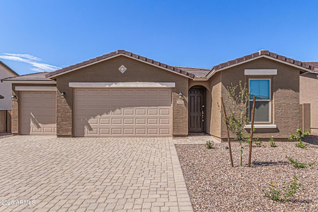 ranch-style house with a tiled roof, decorative driveway, a garage, and stucco siding