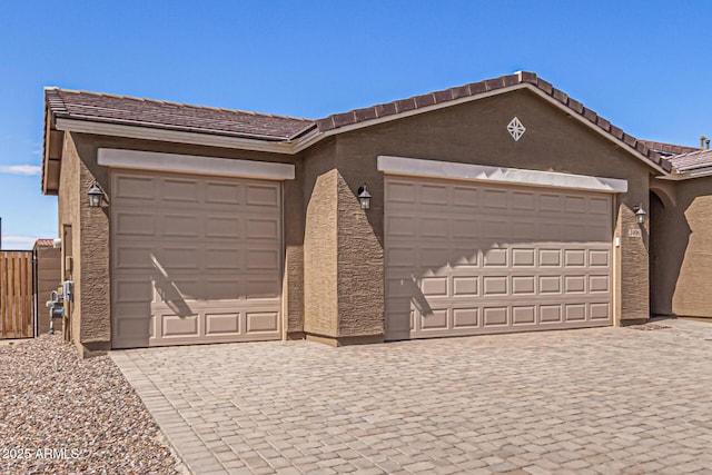 view of front of property with stucco siding, driveway, a garage, and fence