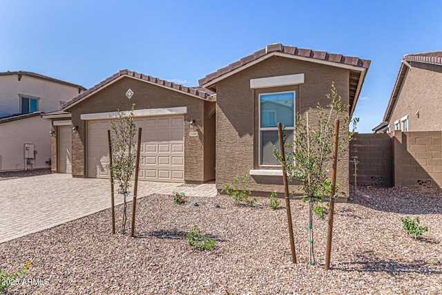 view of front of property featuring decorative driveway, fence, an attached garage, and stucco siding