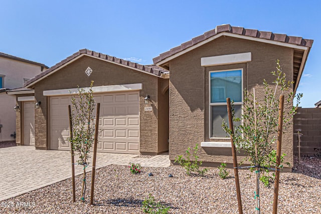 view of front of home with an attached garage, fence, driveway, and stucco siding