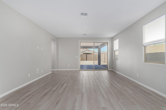 spare room featuring light wood-style flooring, baseboards, and visible vents