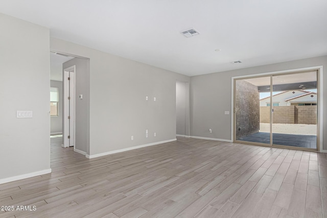 unfurnished room with light wood-type flooring, baseboards, and visible vents