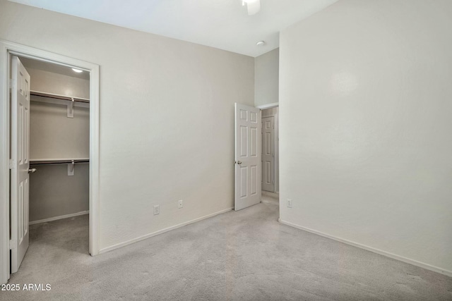 unfurnished bedroom featuring a spacious closet, a closet, and light carpet