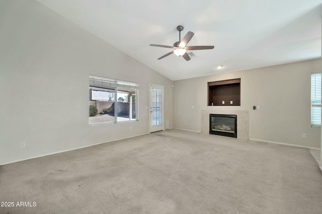 unfurnished living room with light carpet, a wealth of natural light, a high end fireplace, and ceiling fan