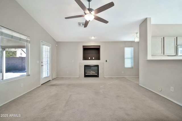 unfurnished living room featuring vaulted ceiling, ceiling fan, light carpet, and a tiled fireplace