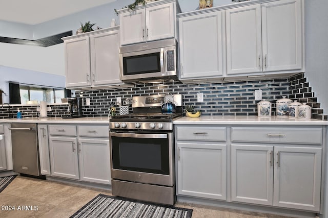 kitchen with stainless steel appliances, backsplash, and gray cabinetry