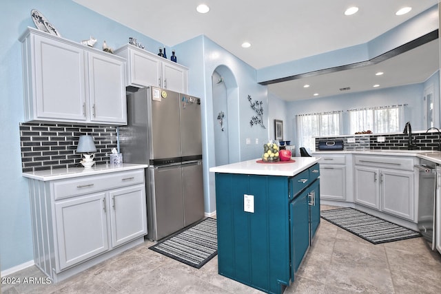 kitchen featuring stainless steel fridge, sink, decorative backsplash, white cabinets, and a center island