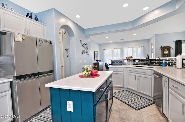 kitchen with light tile patterned floors, sink, stainless steel appliances, a center island, and decorative backsplash