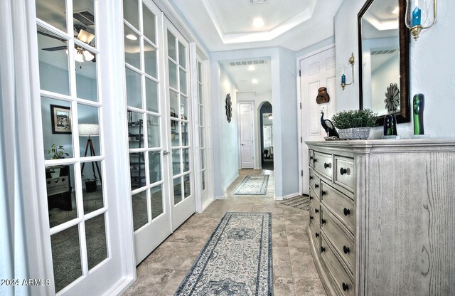 corridor featuring french doors and a tray ceiling