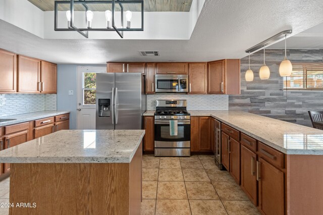 kitchen featuring light stone counters, a textured ceiling, decorative backsplash, stainless steel appliances, and decorative light fixtures