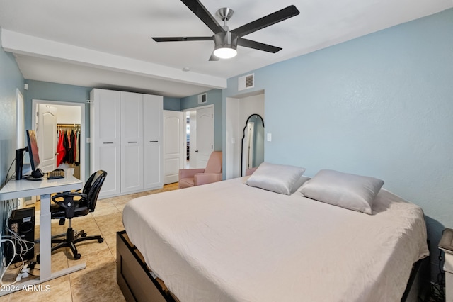 tiled bedroom with a spacious closet, ceiling fan, and a closet