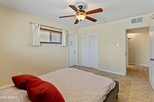 bedroom with baseboards, light tile patterned flooring, ceiling fan, visible vents, and a closet