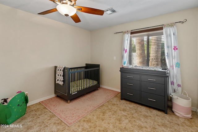 bedroom featuring visible vents, a crib, baseboards, ceiling fan, and light tile patterned floors