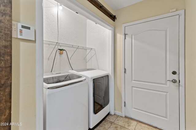 clothes washing area with light tile patterned floors and washing machine and clothes dryer