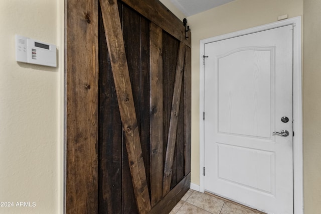 doorway featuring light tile patterned floors and a barn door