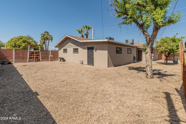 back of property featuring central air condition unit and fence