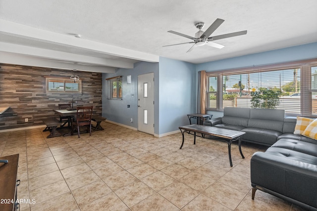 living room with light tile patterned flooring, wood walls, beamed ceiling, and ceiling fan