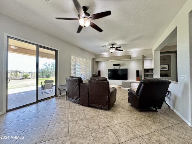 living room featuring ceiling fan, light tile patterned flooring, and a textured ceiling