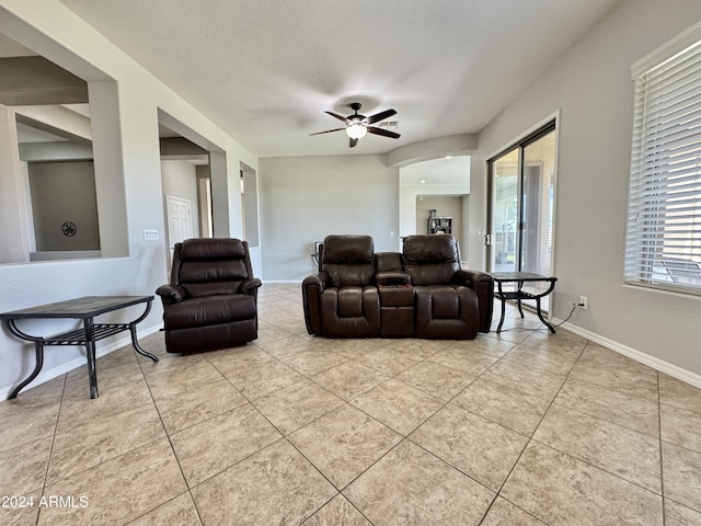 tiled living room with ceiling fan and a textured ceiling