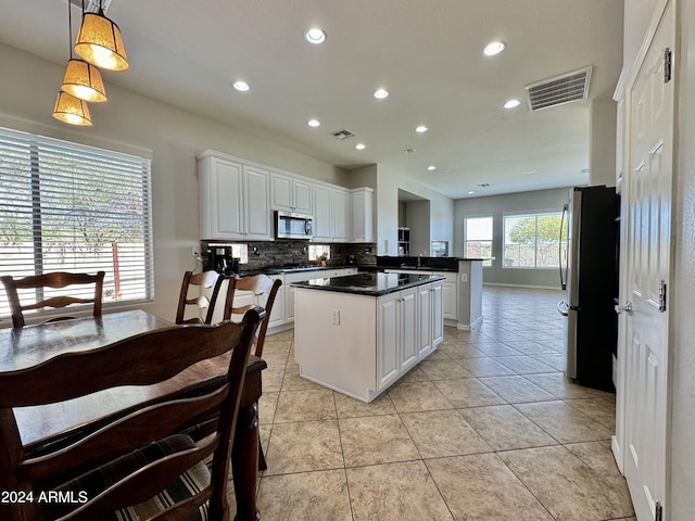 kitchen with light tile patterned floors, kitchen peninsula, pendant lighting, white cabinets, and appliances with stainless steel finishes