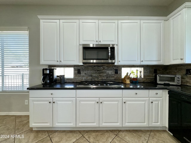 kitchen with white cabinets, appliances with stainless steel finishes, backsplash, and light tile patterned flooring