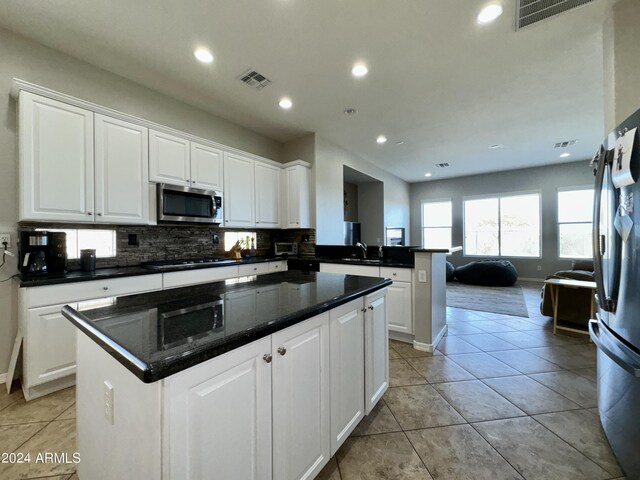 kitchen with white cabinets, light tile patterned flooring, kitchen peninsula, and appliances with stainless steel finishes