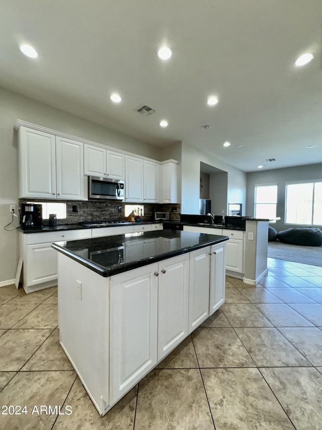 kitchen featuring kitchen peninsula, white cabinets, and light tile patterned flooring