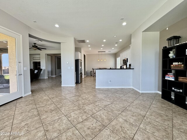 interior space featuring ceiling fan, light tile patterned floors, and a textured ceiling