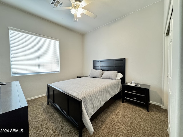 bedroom featuring ceiling fan, dark carpet, and multiple windows