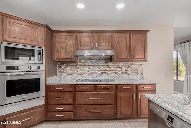 kitchen featuring decorative backsplash, stainless steel appliances, light stone counters, and light hardwood / wood-style floors