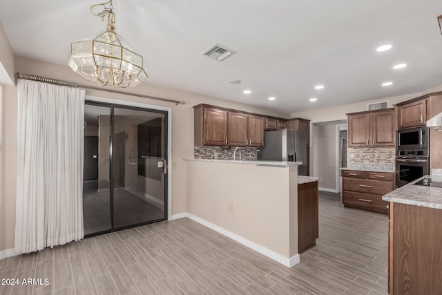 kitchen featuring light stone counters, a notable chandelier, light hardwood / wood-style floors, decorative backsplash, and appliances with stainless steel finishes