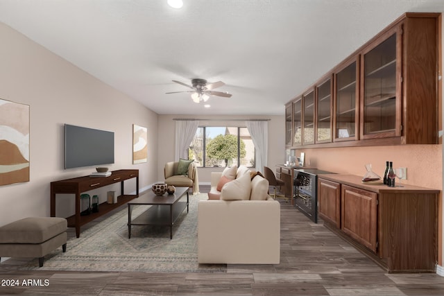 living room with bar, ceiling fan, and dark wood-type flooring