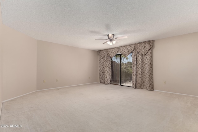 spare room with ceiling fan, light colored carpet, and a textured ceiling