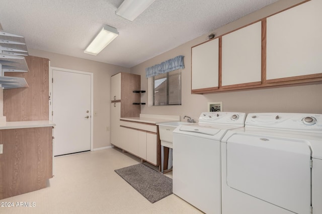 laundry area featuring cabinets, a textured ceiling, washing machine and dryer, and sink