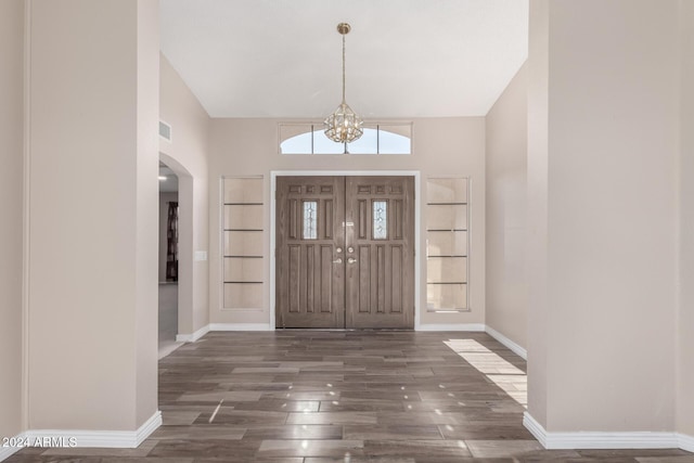 foyer with a notable chandelier, dark wood-type flooring, and high vaulted ceiling