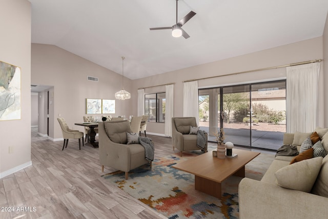 living room with high vaulted ceiling, light hardwood / wood-style floors, and ceiling fan with notable chandelier