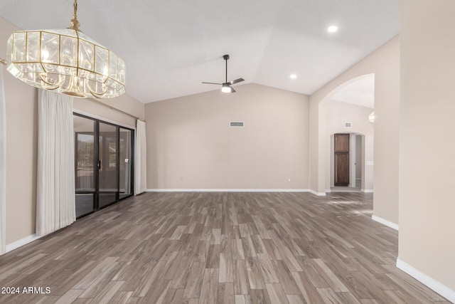 unfurnished living room with ceiling fan with notable chandelier, vaulted ceiling, and hardwood / wood-style flooring