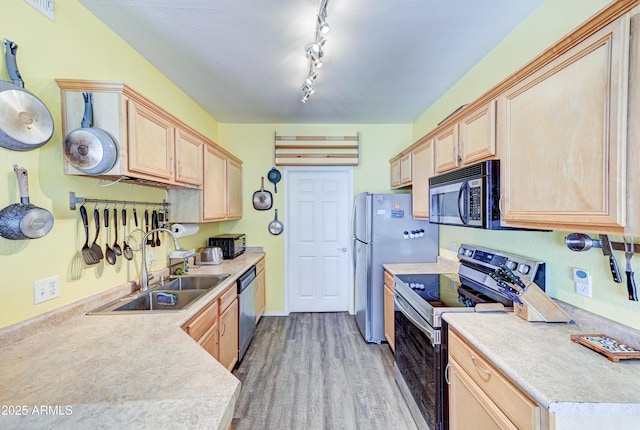 kitchen with light brown cabinetry, appliances with stainless steel finishes, a sink, light countertops, and wood finished floors